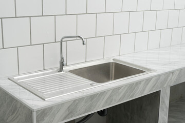 stainless steel kitchen sink detail on white granite worktop at home