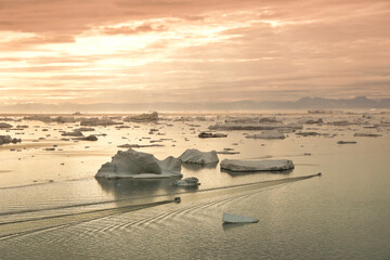 Boats leaving harbor at 10:00 p.m. in summer (Midnight Sun) to fish among icebergs in Disko Bay,...