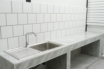stainless steel kitchen sink detail on white granite worktop at home