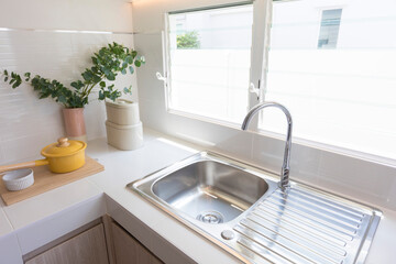 stainless steel kitchen sink detail on white granite worktop at home