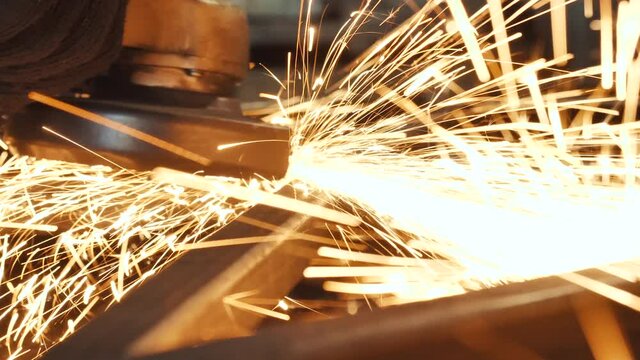 Grinding work with smooths equipment for steel metal, iron, sparks at manufacturing heavy industry factory closeup indoor. Metalwork assembly, heat detail welding by professional laborer using grinder