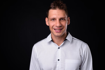 Portrait of happy businessman against black background