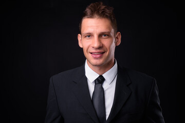 Portrait of happy businessman in suit against black background