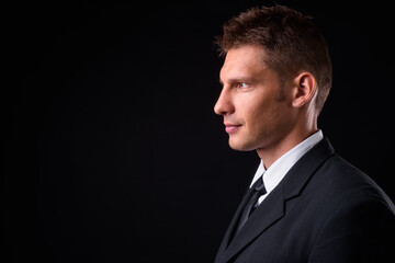 Portrait of businessman in suit against black background