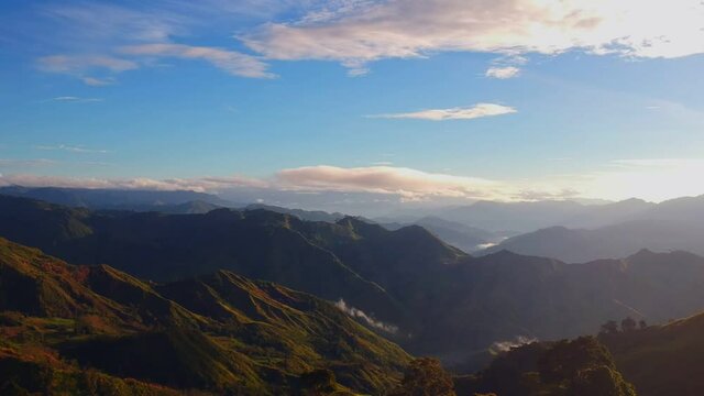 Panoramic drone shot of mountain ridges and rainforest in the foreground