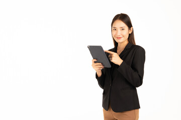An asian business womanin a black suit stands smiling using the taplat look at the camera ,isolated on white background.