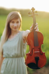 Violin in the hands of a young female violinist in the sunset light. woman, girl