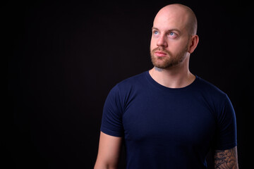 Obraz premium Handsome bald bearded man against black background