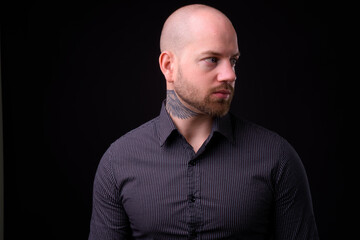 Handsome bald bearded businessman against black background