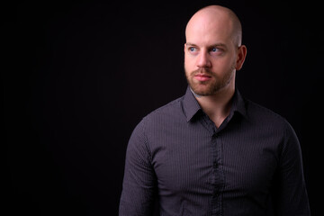 Handsome bald bearded businessman against black background