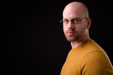 Handsome bald bearded man against black background