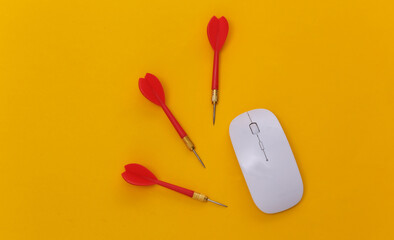 Pc mouse and darts on yellow background. Top view