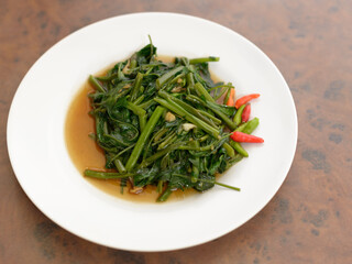 Stir fried water spinach on wooden table