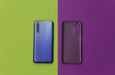 Smartphone with a silicone protective cover on green purple background. Top view