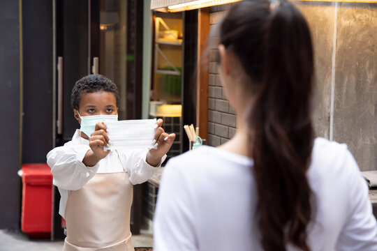 African Woman, Black Small Business Owner Asking The Customer To Wear Face Mask Or Face Covering Cloth; Concept Of Face Mask Mandate, No Mask No Entry, Social Distancing, New Normal Business Practice