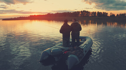 Two anglers fishing on the river at sunset
