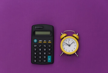 Calculator and alarm clock on a purple background. Top view. Flat lay