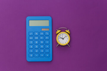 Calculator and alarm clock on purple background. Top view. Flat lay