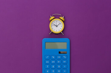 Calculator and alarm clock on purple background. Top view. Flat lay