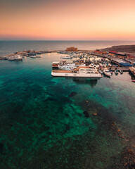 Beautiful aerial sunset shot of Paphos Castle and Paphos Harbor in Cyprus. Crystal clear water, fishing boats, luxury yachts - amazing travel destination for all year vacation. 