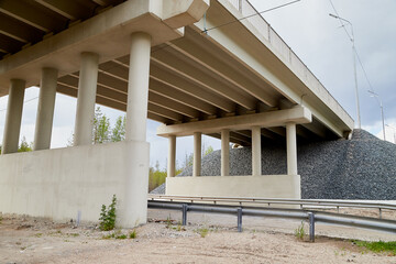 Bottom view of the prestressed concrete beams and piers of bridge crossing many-lane expressway of road.