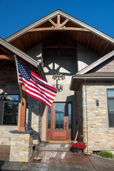 From porch of a modern home with stone veneer, columns, arches, and an American flag.
