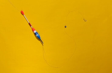 Fishing float with a hook on a bright yellow background