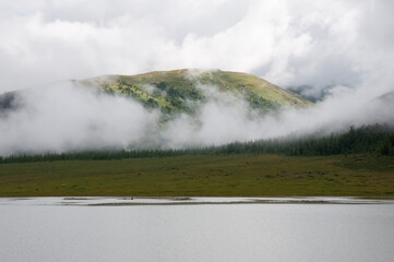 Landscape view of Altai mountains covered in the morning fog with lake Akkem in the foreground, Russia, the Altai Republic