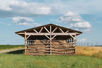 Wooden facility for storage of hay bales at the cattle farm.