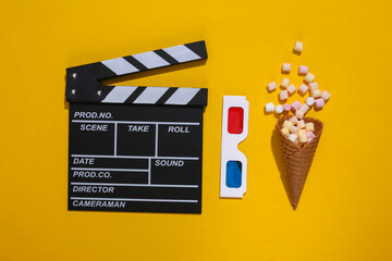 Movie clapboard, ice cream waffle cone with popcorn, 3d glasses on yellow background with deep...