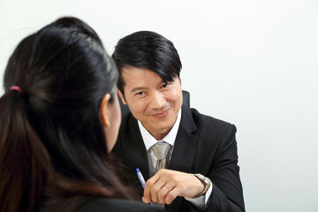 Young Asian male female wearing suit sitting at office desk look at camera over the shoulder