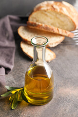 Obraz na płótnie Canvas Bottle of tasty olive oil and bread on dark background