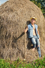 Naklejka na ściany i meble young cowboy with a pitchfork and a haystack