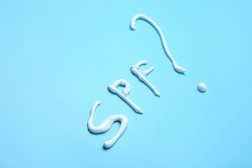 SPF written with sunscreen cream on color background