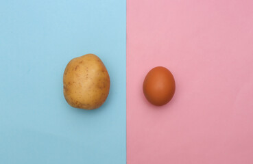 Chicken egg and potato on pink blue pastel background. Top view