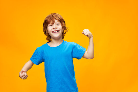 Boy with red hair gestures with his hands and blue t-shirt