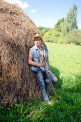 young cowboy with a pitchfork and a haystack