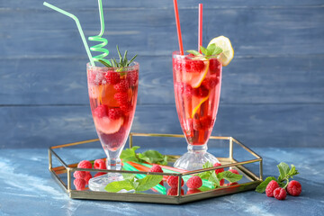 Glasses of cold raspberry tea on color background