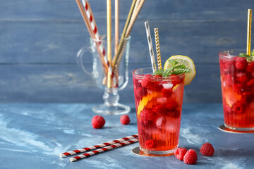 Glass of cold raspberry tea on color background