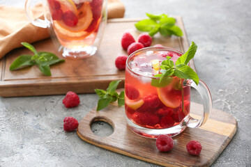 Cup of cold raspberry tea on grey background