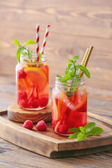 Mason jars of cold raspberry tea on table