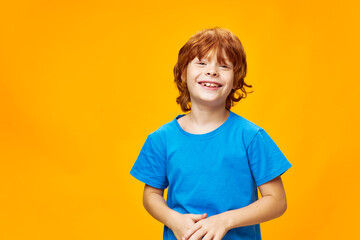 Happy red-haired boy smiling at the camera on a yellow background  © SHOTPRIME STUDIO