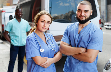 Portrait of male and female paramedicals near ambulance car outdoor
