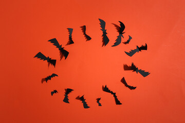Flying bats on orange bright background. Halloween background. Top view. Flat lay