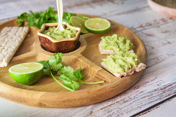 green guacamole on the wooden table with toasts