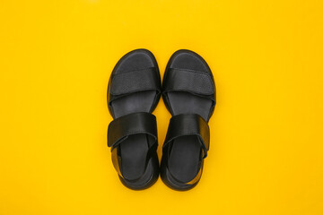 Leather black women's sandals on a yellow background. Top view. Flat lay