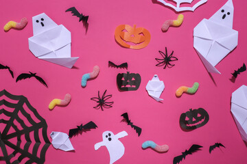 Handmade Halloween decor and gummy worms on pink background. Halloween background. Top view. Flat lay