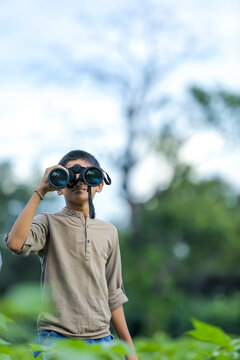 little Indian boy enjoys in nature with binoculars