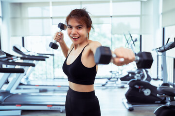 Fototapeta premium asian women cheerful while lifting dumbbells workout in gym, lifestyle young female exercising weight training for healthy