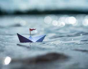 Kleines Papierschiff auf glitzerndem See